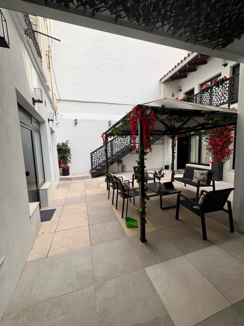 Amplio patio con pérgola en Be Gonfre Flats Valencia, área de comedor, enredaderas con flores rojas y pavimento moderno