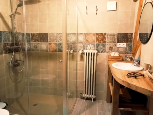 Salle de bain moderne avec douche spacieuse, carrelage décoratif, meuble vasque en bois et radiateur blanc au gîte Paulusmühle