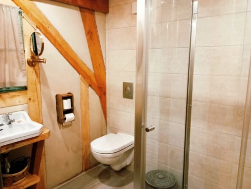 Salle de bain moderne du gîte Paulusmühle à Soucht avec poutres en bois, lavabo, toilettes et douche à l'italienne