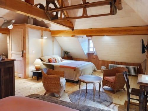 Chambre de la chaumière Paulusmühle avec poutres en bois, lit, fauteuils en osier et décor rustique à Soucht, France