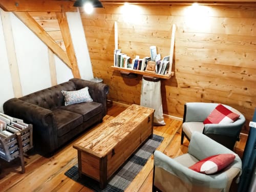 Intérieur chaleureux de chalet en bois avec canapé foncé, fauteuils et table en bois à la Paulusmühle BnB à Soucht