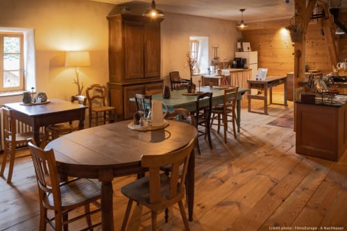 Intérieur chaleureux du chalet en bois Paulusmühle avec table ronde, mobilier rustique et cuisine ouverte à Soucht