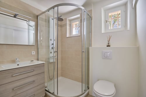 Salle de bains moderne avec douche à paroi courbe en verre, vasque et toilettes à la villa CIRELINE à Rognes