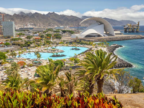Vista costera de Santa Cruz de Tenerife con piscina turquesa, arquitectura moderna, montañas y océano