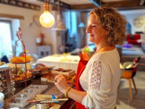 Femme en cardigan crème à la cuisine du gîte de l'Île d'Yeu, ambiance chaleureuse et décoration colorée