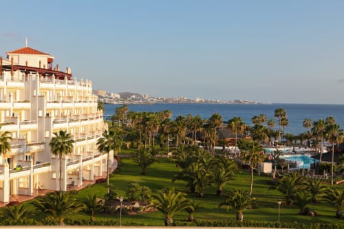 Luxury beachfront apartment in Santa Cruz de Tenerife with ocean views, palm trees, and pool area overlooking the coast.