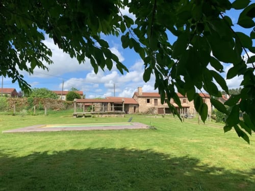 Los terrenos del hotel O Lagar De Jesus en Padrón con césped exuberante, edificios de piedra y frondoso dosel de árboles