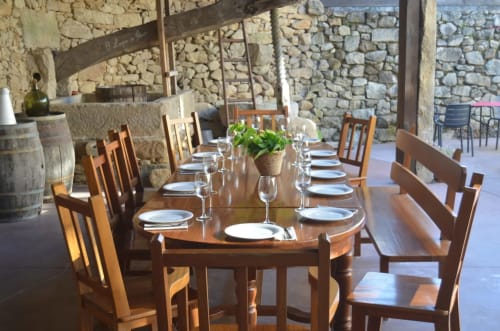 Elegante comedor del hotel O Lagar De Jesus en Padrón con mesa de madera, cubiertos y paredes de piedra.