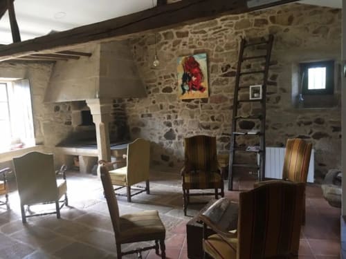 Interior rústico de piedra en el hotel O Lagar De Jesus en Padrón con muebles de madera, chimenea y vigas vistas.