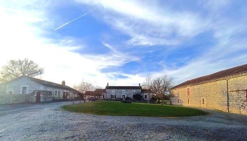 Domaine de Beau Site courtyard with stone buildings and green lawn, Peyrat-de-Bellac, France