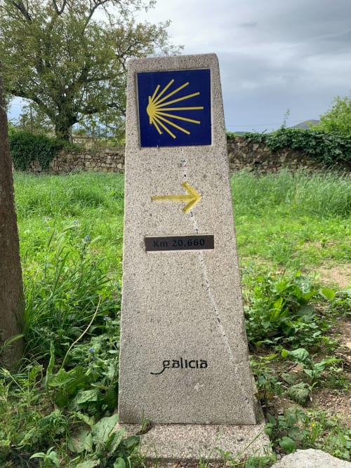 Camino de Santiago waymarker showing golden scallop shell and arrow at km 20,660 near Padrón, Galicia