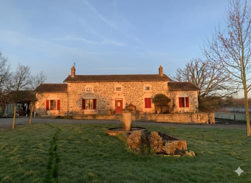 Domaine de Beau Site BnB, a rustic stone farmhouse in Peyrat-de-Bellac, France, with red shutters and chimney.