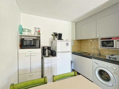 Cuisine compacte de l'Appartement 124 à Le Vallon des Sources, Digne-les-Bains, avec placards blancs, électroménagers et lave-linge.