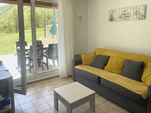 Canapé jaune dans l'appartement Le Vallon des Sources avec vue sur la terrasse, Digne-les-Bains