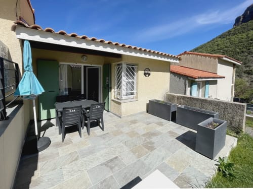 Terrasse ensoleillée de l'Appartement 124 au Vallon des Sources à Digne-les-Bains avec vue sur les montagnes, table à manger, transats et