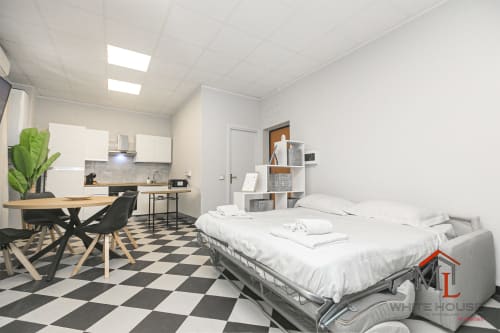 Monolocale moderno a Genova con letto, angolo cottura, zona pranzo, pavimento a scacchi e vista sulla città