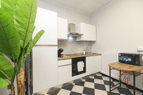 Cucina moderna dell'appartamento ML White House a Genova, con mobili bianchi, forno nero, ripiani in legno e pavimento a scacchiera