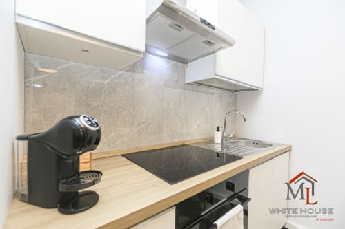Moderna cucina nell'appartamento ML White House di Genova con piano in legno, piano cottura nero e rivestimento in marmo
