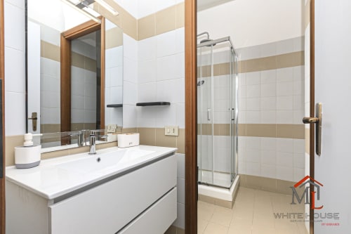 Bagno moderno con lavabo bianco, specchio e doccia con box in vetro alla ML White House di Genova