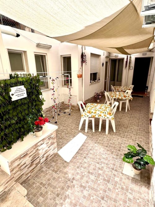 Trapani apartment courtyard with white chairs, sunshade, potted plants, and ground-floor patio dining area