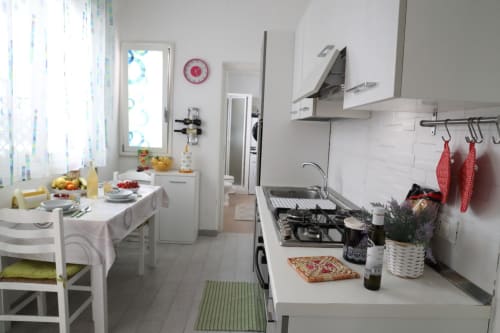 Modern kitchen and dining area in Casa Vacanze La Coccinella apartment, Trapani with white cabinetry, cooking appliances and