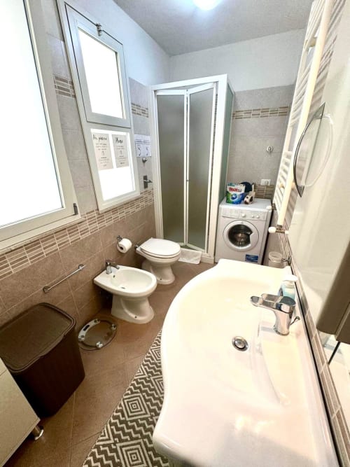 Modern bathroom with bathtub, toilet, bidet, and washing machine at Casa Vacanze La Coccinella apartment in Trapani