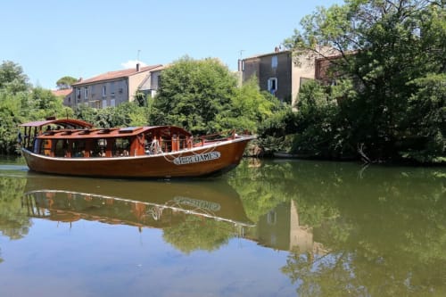 Wooden boat moored on calm river with traditional buildings in Vendrest, France
