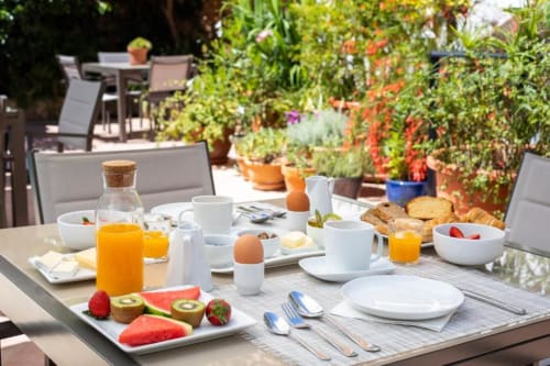 Breakfast spread on garden terrace at Casa Sibarita with fresh fruit, pastries, orange juice, and coffee overlooking