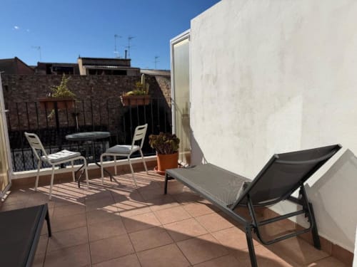 Sunny terrace at Casa Sibarita with lounge chairs, white chairs, table, and potted plants overlooking garden in Rafelguaraf