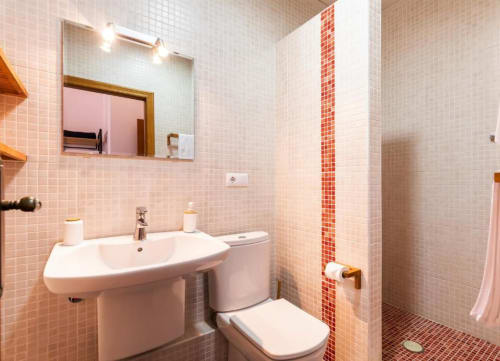Modern bathroom with pink mosaic tiles, sink, toilet, and walk-in shower at Casa Sibarita hotel in Rafelguaraf, Spain