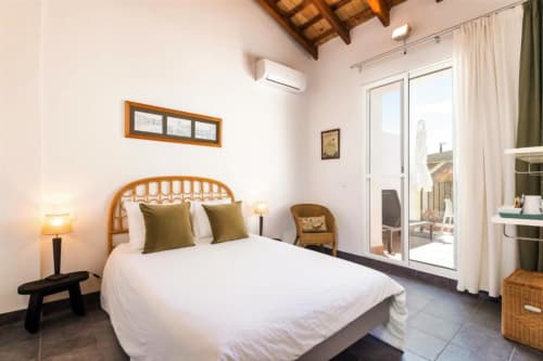 Deluxe double room at Casa Sibarita with rattan headboard, white bedding, terrace access, and garden views