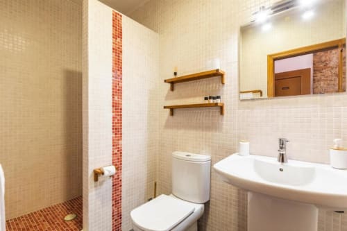 Modern bathroom at Casa Sibarita with white tiles, red mosaic accent stripe, floating shelves, and walk-in shower in
