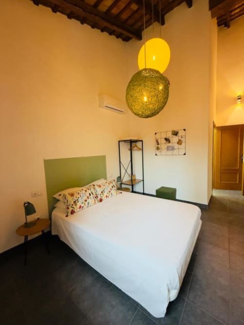 Premium double room at Casa Sibarita with green headboard, white linens, yellow pendant lights, and tile flooring