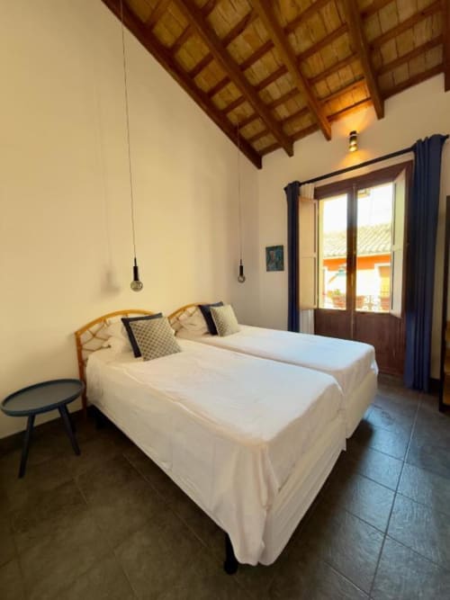 Modern bedroom at Casa Sibarita in Rafelguaraf with two beds, wooden beamed ceiling, and balcony with city views