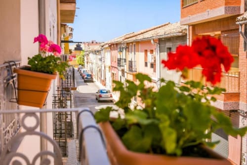 Balcony view of colorful colonial buildings and street in Rafelguaraf with flowering potted plants at Casa Sibarita