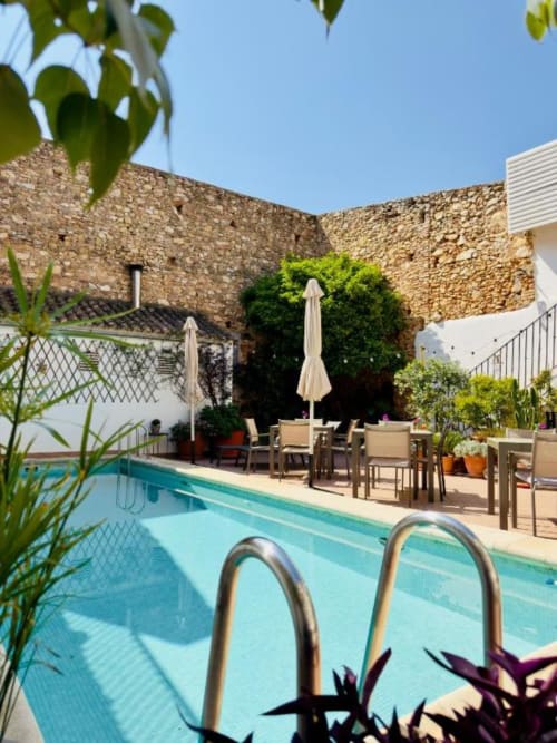 Casa Sibarita's garden pool terrace with stone castle walls, dining area under umbrella, and loungers in Rafelguaraf