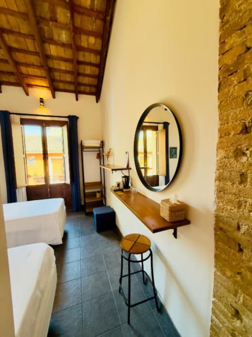 Spacious bathroom at Casa Sibarita hotel in Rafelguaraf with oval mirror, wooden vanity, and soaking tub with city views