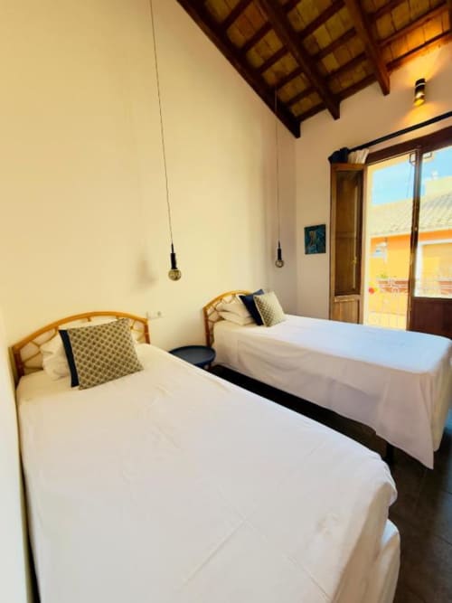 Twin beds in a bright Casa Sibarita hotel room with city views, wooden beams, and balcony access in Rafelguaraf