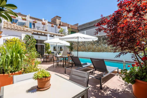 Casa Sibarita luxury terrace with pool view, lounge chairs, umbrellas, red ivy, potted plants and dining area in Rafelguaraf,