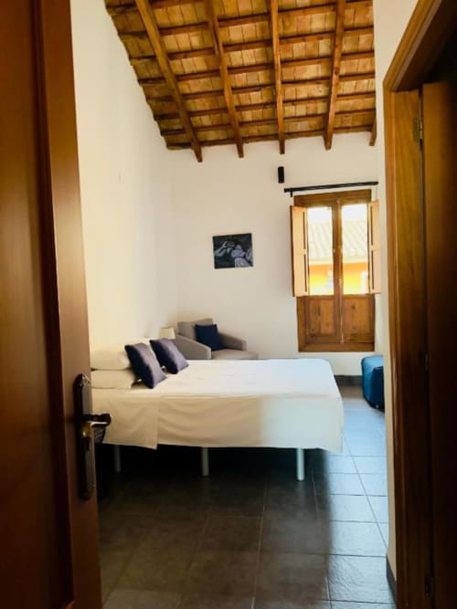 Premium double room at Casa Sibarita hotel in Rafelguaraf with wooden beam ceiling, white bed, and city view through glass