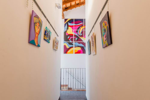 Casa Sibarita hallway with colorful artwork displayed on beige walls and vibrant street art mural visible ahead, Rafelguaraf