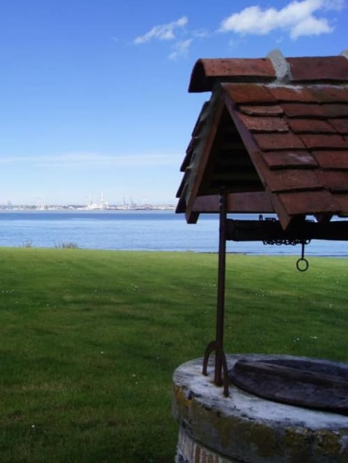 Balançoire rustique surplombant la baie bleue du gîte La Girelle à Honfleur, France avec voiliers au loin