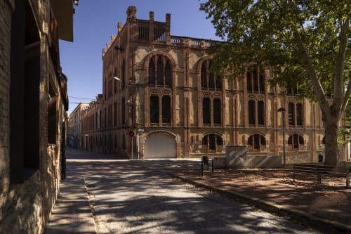 Façana històrica de maó de l'Hotel Restaurant Can Carol a Capellades, Espanya, amb pati i ombra d'arbres