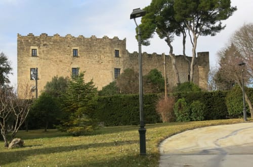 Exterior de pedra de l'Hotel Restaurante Can Carol, un castell a Capellades amb jardins ben mantinguts i farola