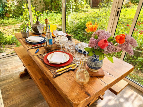 Elegant dining table set with red plates and colorful flowers overlooking La Villa Malzy garden in France