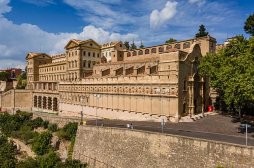 Historic Hotel Can Carol amb murs de pedra i edificis beige a Capellades, Espanya sota cel blau