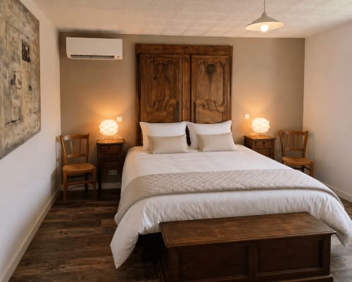 Elegant bedroom at La Villa Malzy cottage with wooden headboard, white bedding, warm lighting, and garden view