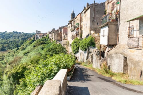 Via storica del villaggio collinare di Campagnano di Roma con antichi edifici in pietra e viste sulla campagna verde e lussureggiante