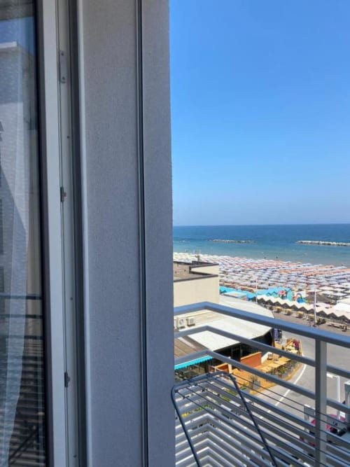 Vista dal balcone della Junior Suite dell'Hotel Vienna di Pesaro, con affaccio sulla spiaggia affollata e il Mar Adriatico