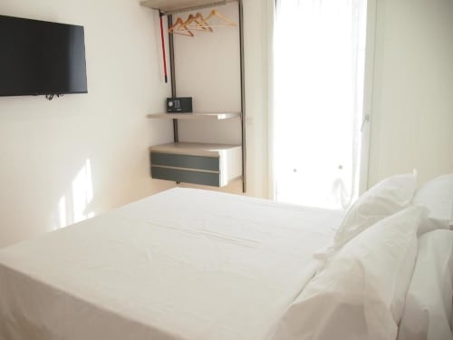 Camera Junior Suite moderna dell'Hotel Vienna a Pesaro con biancheria bianca, TV a parete, angolo cottura e balcone con vista mare